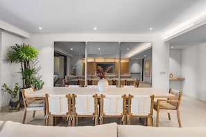 A modern dining area with a large table, wooden chairs, and a central vase. - Casa Lua: Golf Views & Breakfast Prep in Punta Mita (Desarrollo Punta Mita)
