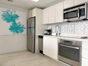 Eine moderne Küche mit Edelstahlgeräten, einer Fliesenküchenwand und einem minimalistischen Design.