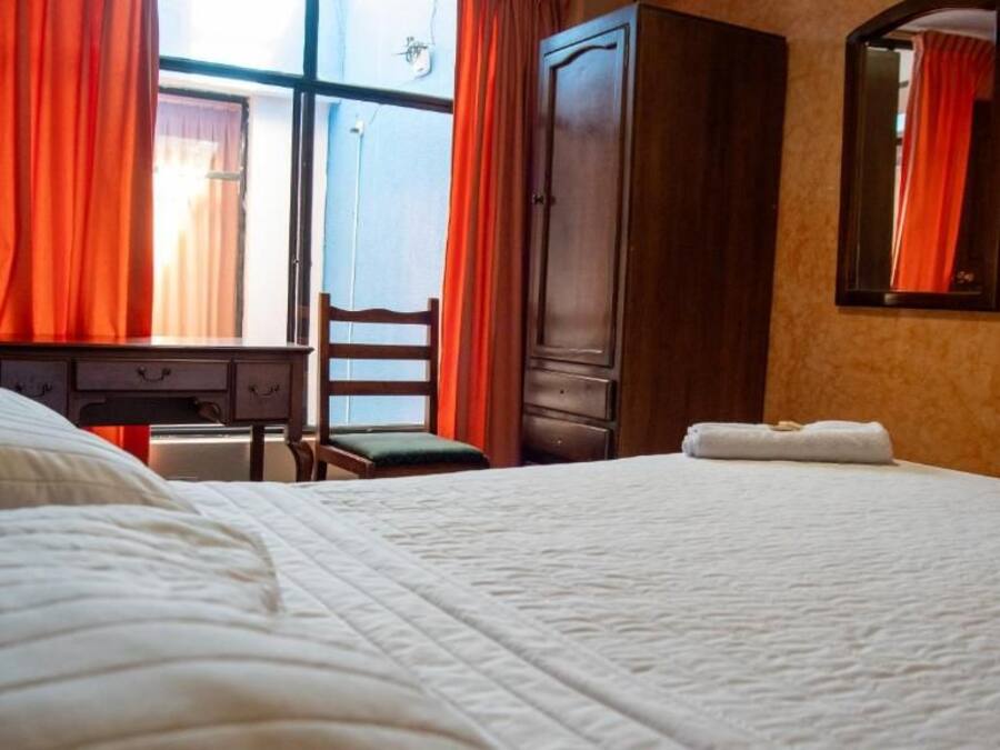 A hotel room with a bed, a desk, a chair, and a wardrobe.
