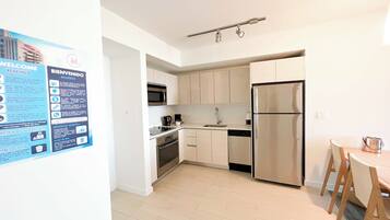 A modern kitchen with stainless steel appliances, a dishwasher, and a dining area with a wooden table and chairs.