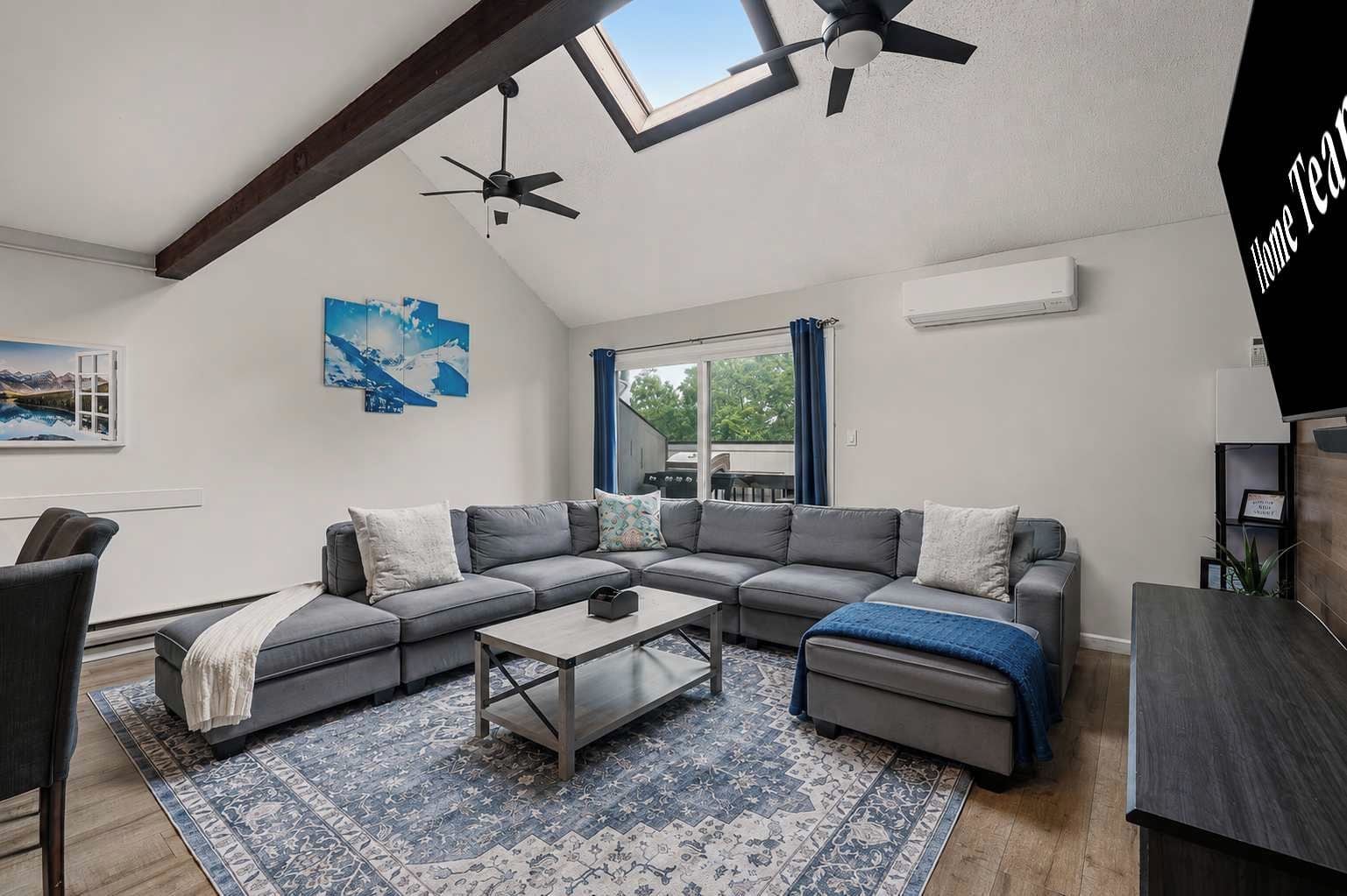 Een moderne woonkamer met een hoekbank, een salontafel en een plafondventilator.