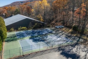 An outdoor tennis court with a fenced area, surrounded by trees and a building. - Camelback Mountain Escape | Sleeps 12 (Tannersville)
