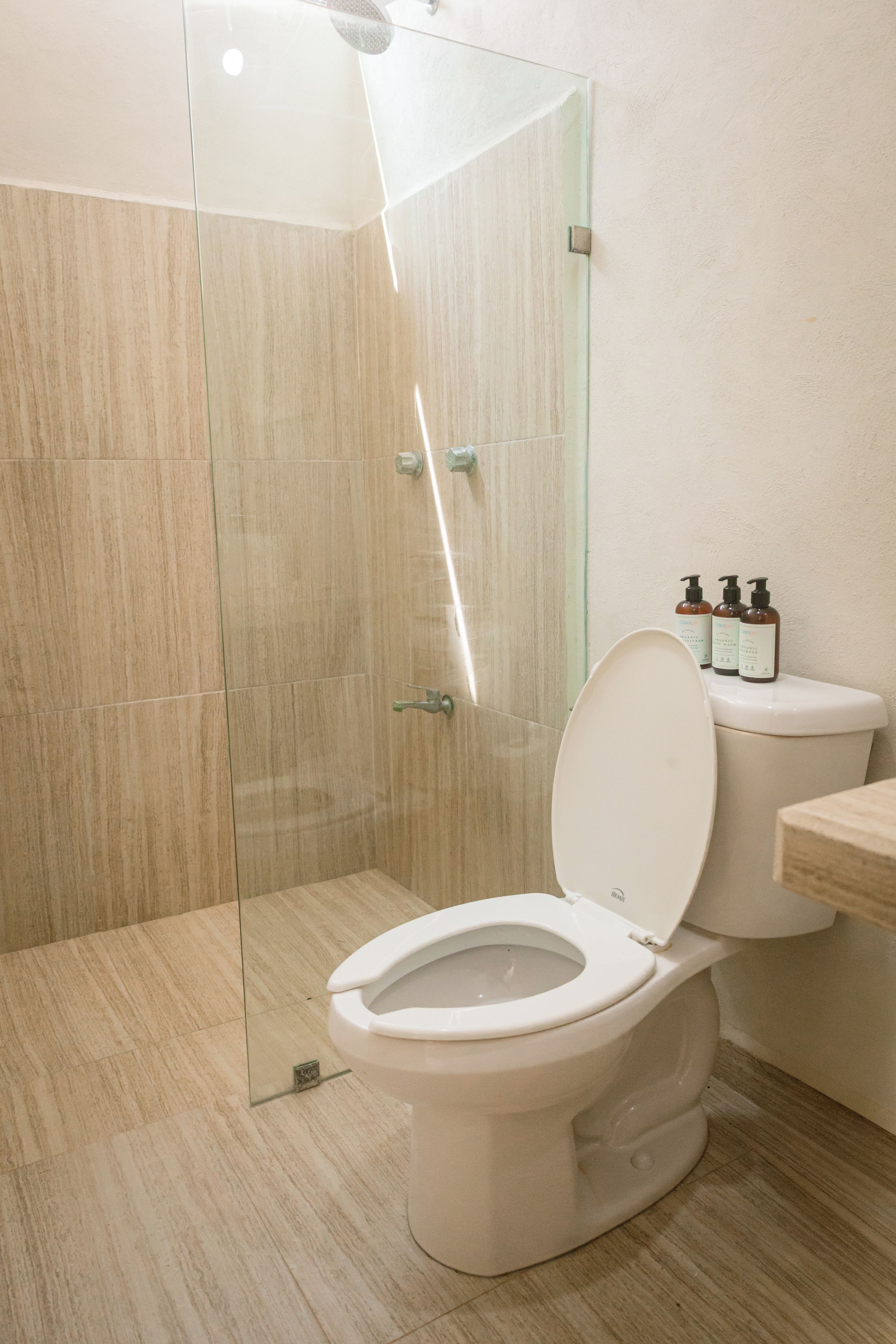 Un baño moderno con cabina de ducha de vidrio, inodoro y artículos de aseo en la encimera.