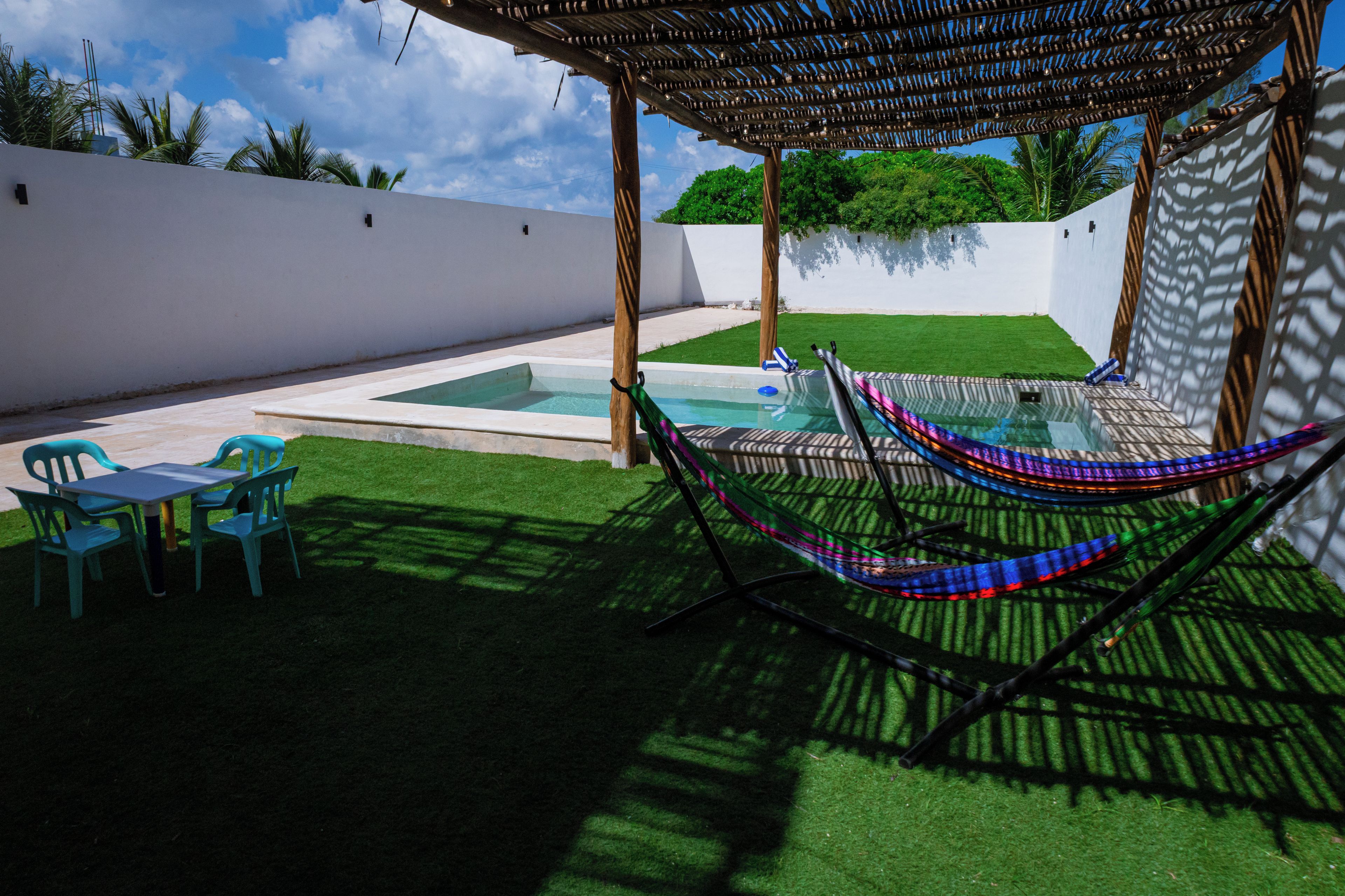 Un área de piscina con una hamaca, una mesa y sillas.