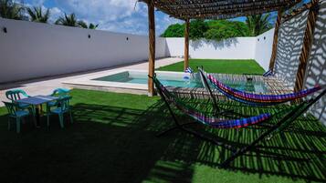 A pool area with a hammock, a table, and chairs.