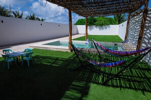 Un área de piscina con una hamaca, una mesa y sillas.