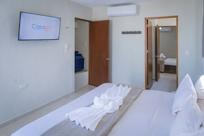 Ein Hotelzimmer mit Bett, Wandfernseher und einer Tür zum Badezimmer.