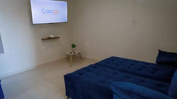 A room with a large bed, a small table with a plant, and a TV displaying 'Casago Vacation Rentals'.