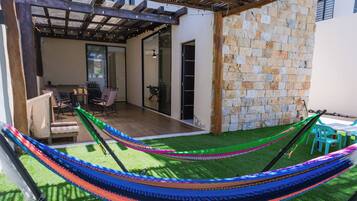 Un patio con una hamaca, una mesa de comedor y sillas.