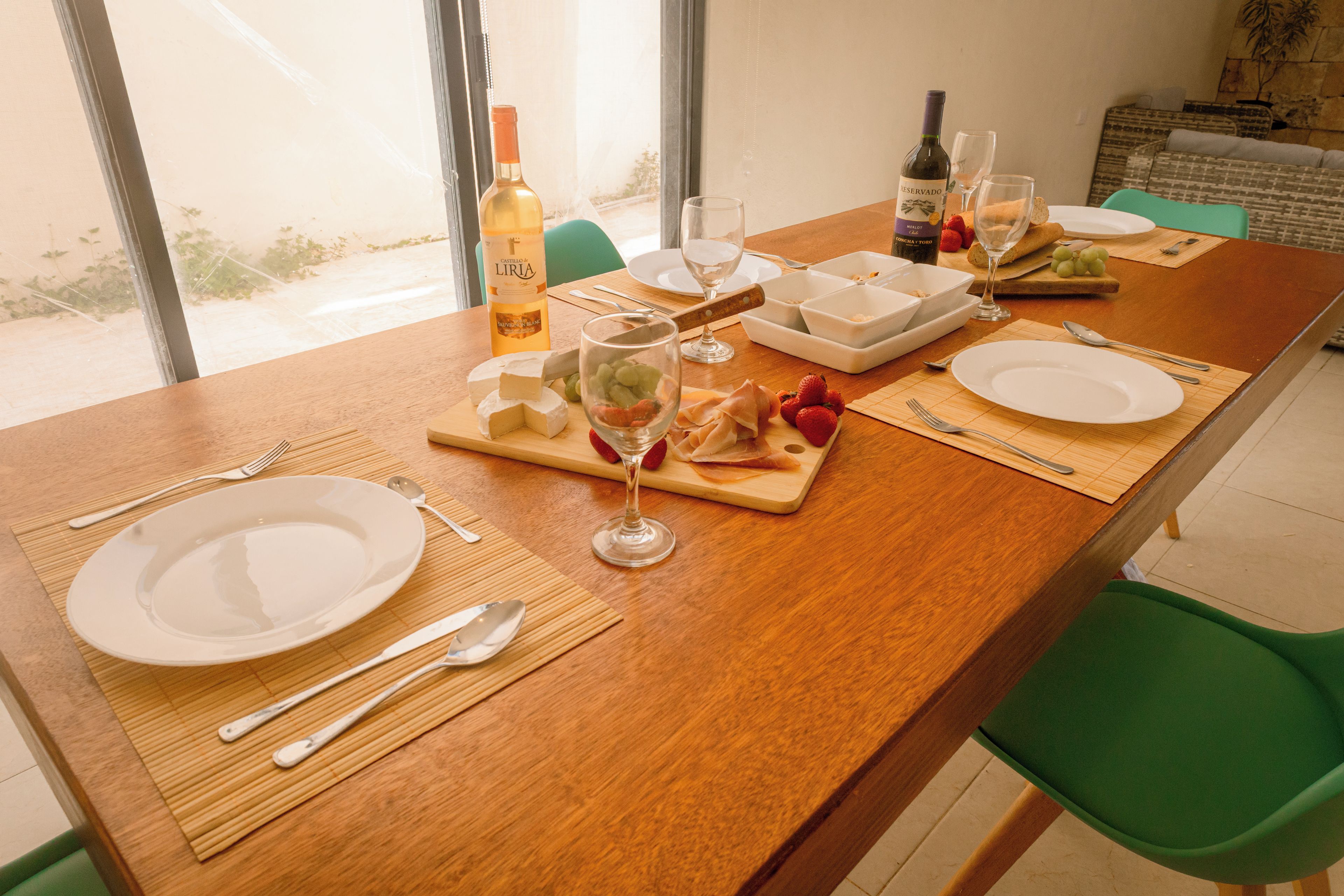 A dining table set with plates, cutlery, glasses, and a bottle of wine.