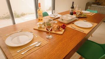 A dining table set with plates, cutlery, glasses, and a bottle of wine.