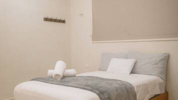 A bedroom with a wooden bed, a grey blanket, and a ceiling fan.