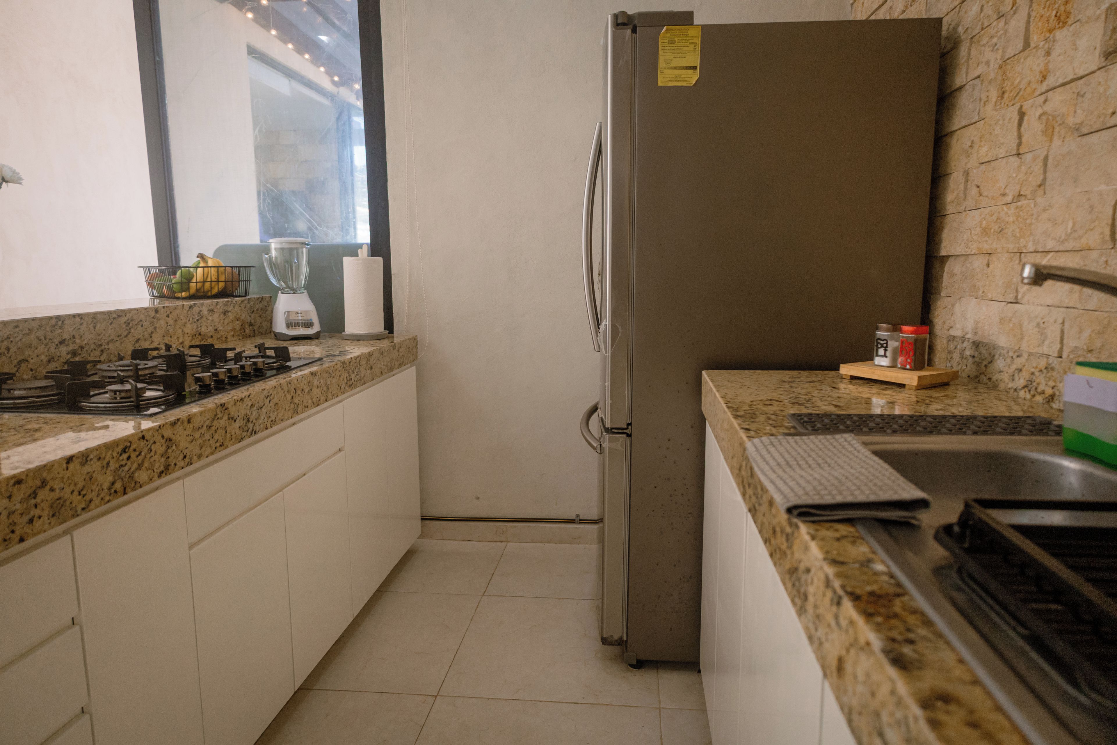 Une cuisine de taille réduite équipée d’un réfrigérateur, d’une cuisinière et d’un évier.
