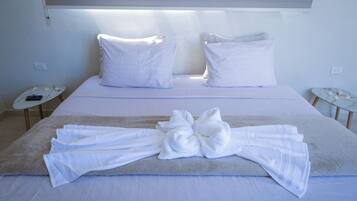 A neatly made bed with white linens and a towel arranged in a bow on the bed.