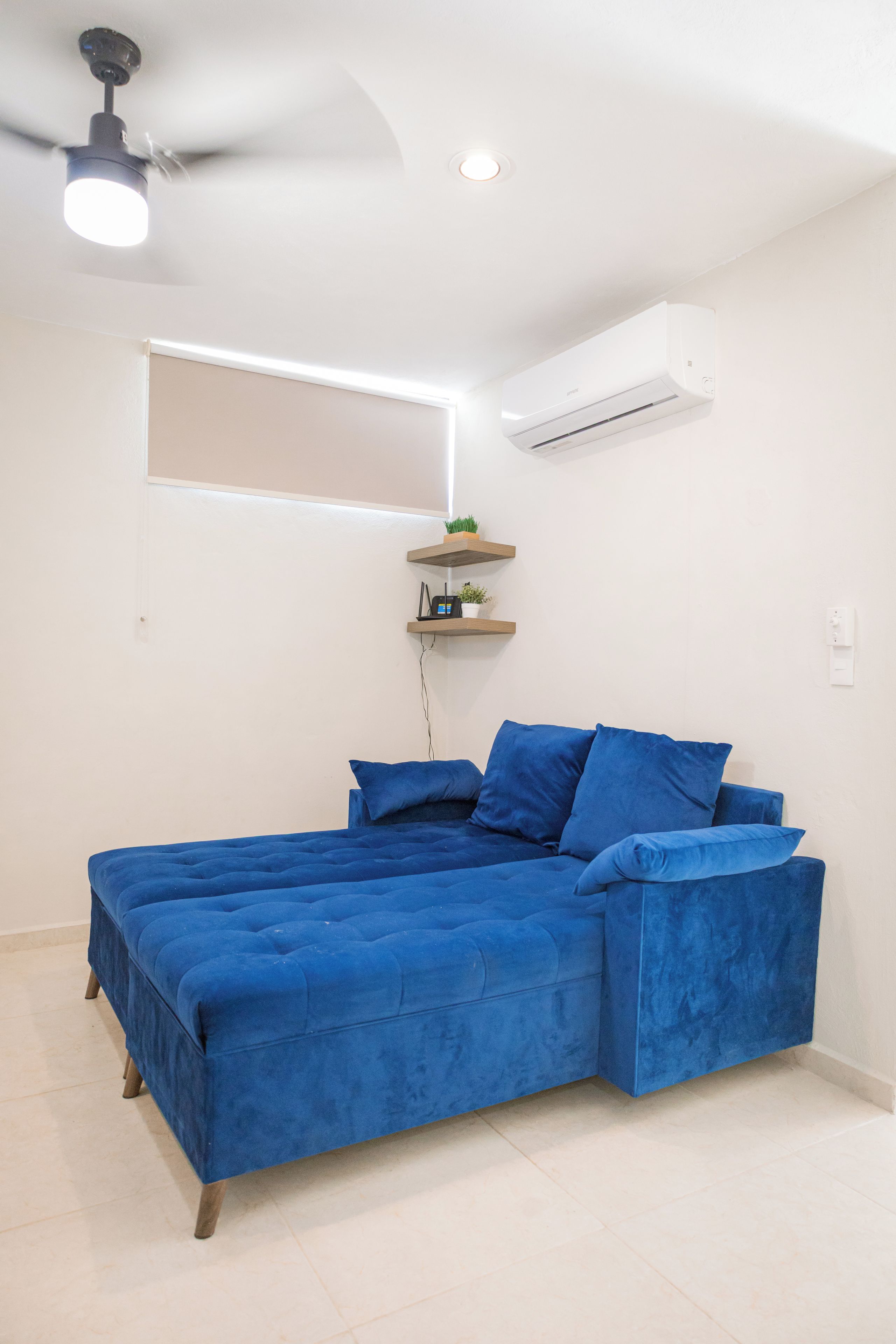 Una habitación con cama, aire acondicionado, ventilador de techo y ventana.