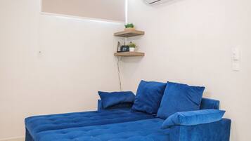 A room with a bed, an air conditioning unit, a ceiling fan, and a window.