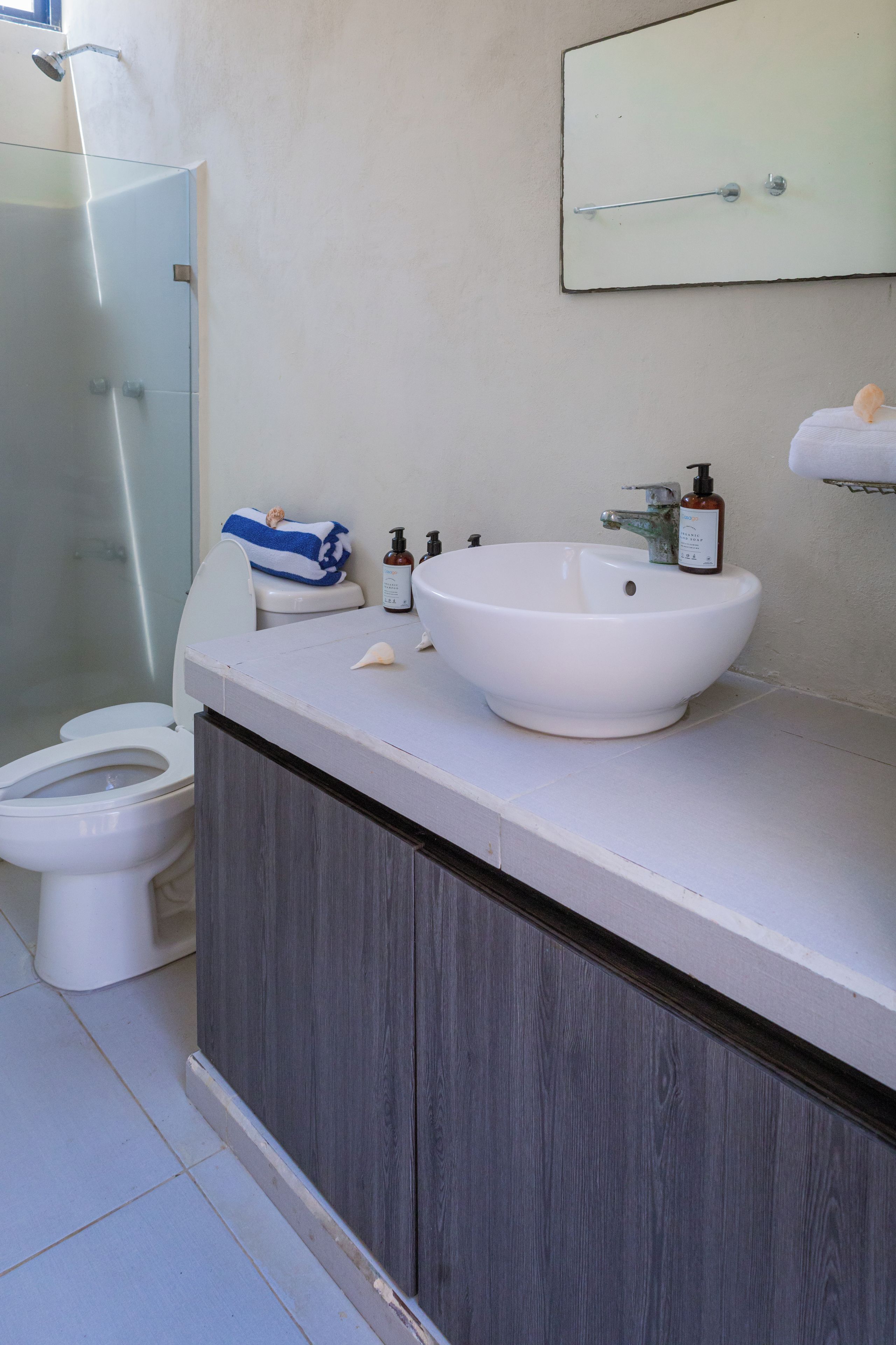 Une salle de bain avec un lavabo blanc, une cabine de douche en verre et des toilettes.