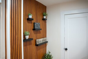 A wall with vertical wooden slats, three black shelves with potted plants, and two signs with motivational quotes. - A Scenic Townhouse Near  Amherst (Next to a Horse Farm) (Sunderland)