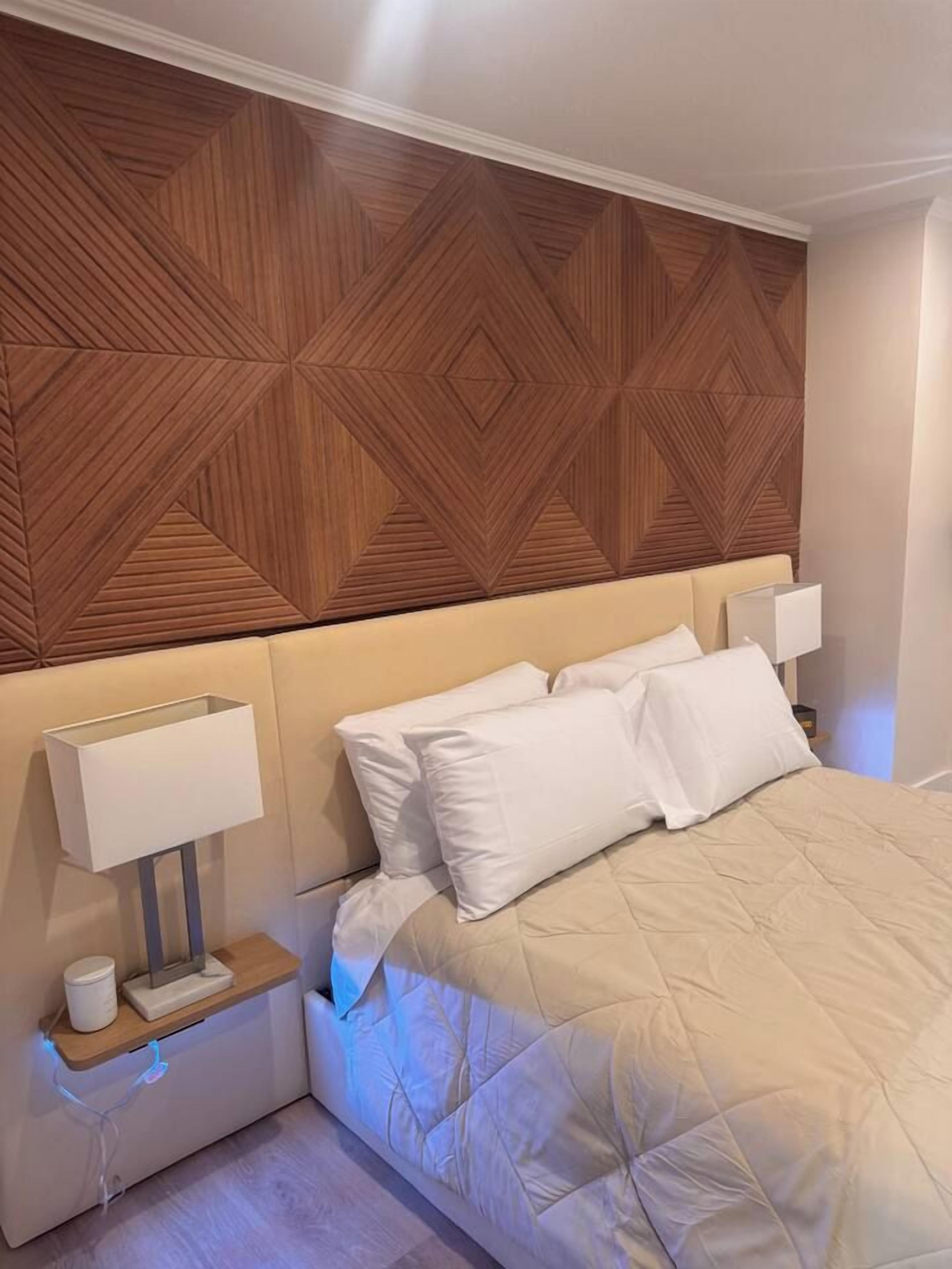 A hotel room with a bed, bedside tables, and a wooden headboard.