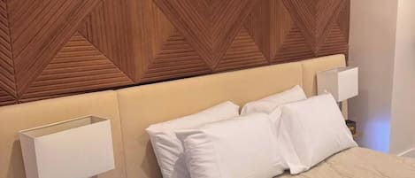 Una habitación de hotel con cama, mesitas de noche y cabecero de madera.