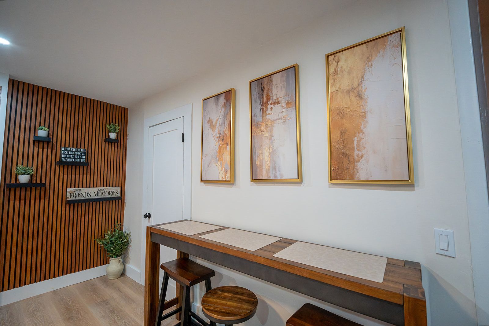 A reception area with a wooden slat wall, a reception desk, and three framed abstract paintings.