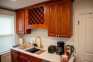 Una cocina con armarios de madera, un lavamanos, una cafetera y un tostador.