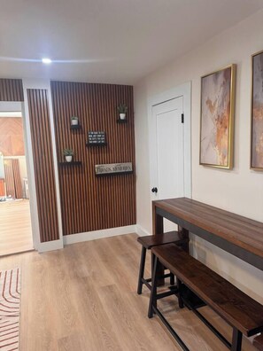 A room with a wooden bench, a white door, and a wall-mounted sign.