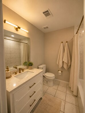A bathroom with a sink, mirror, toilet, and shower. -     30+ Day Stay - Travel Nurses & Work Crews (Tuscaloosa)