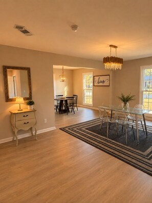 A spacious living room with a dining area, a chandelier, and a large mirror. -     30+ Day Stay - Travel Nurses & Work Crews (Tuscaloosa)