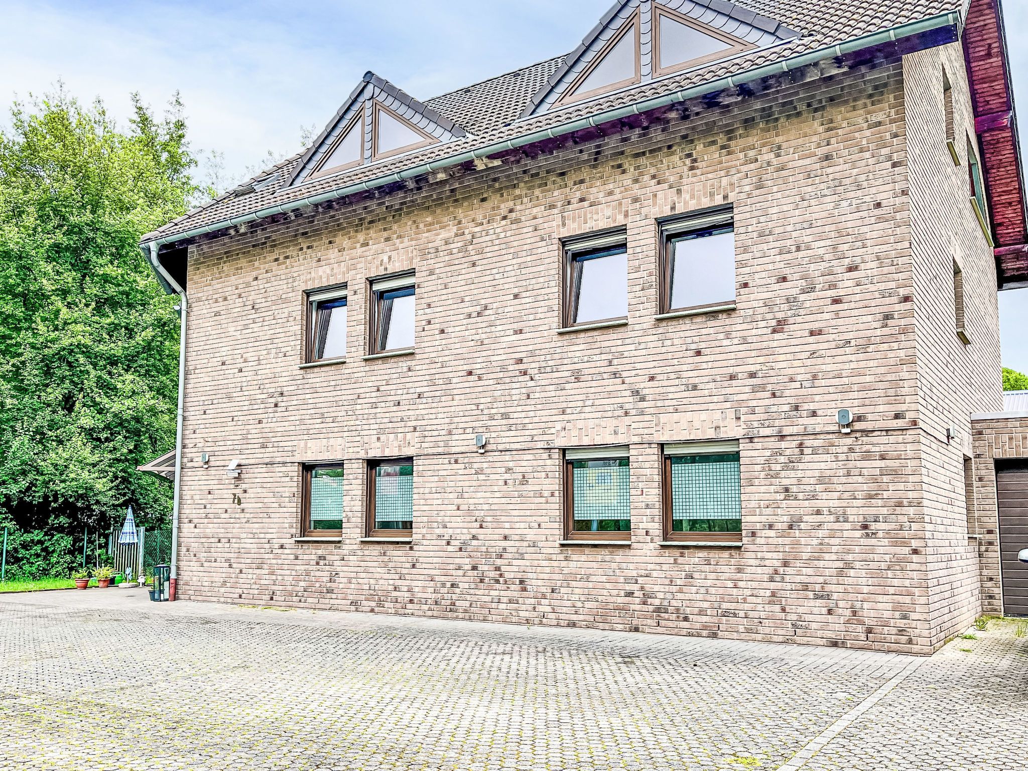 Een gebouw met twee verdiepingen, een bakstenen gevel, meerdere ramen en een schuin dak.