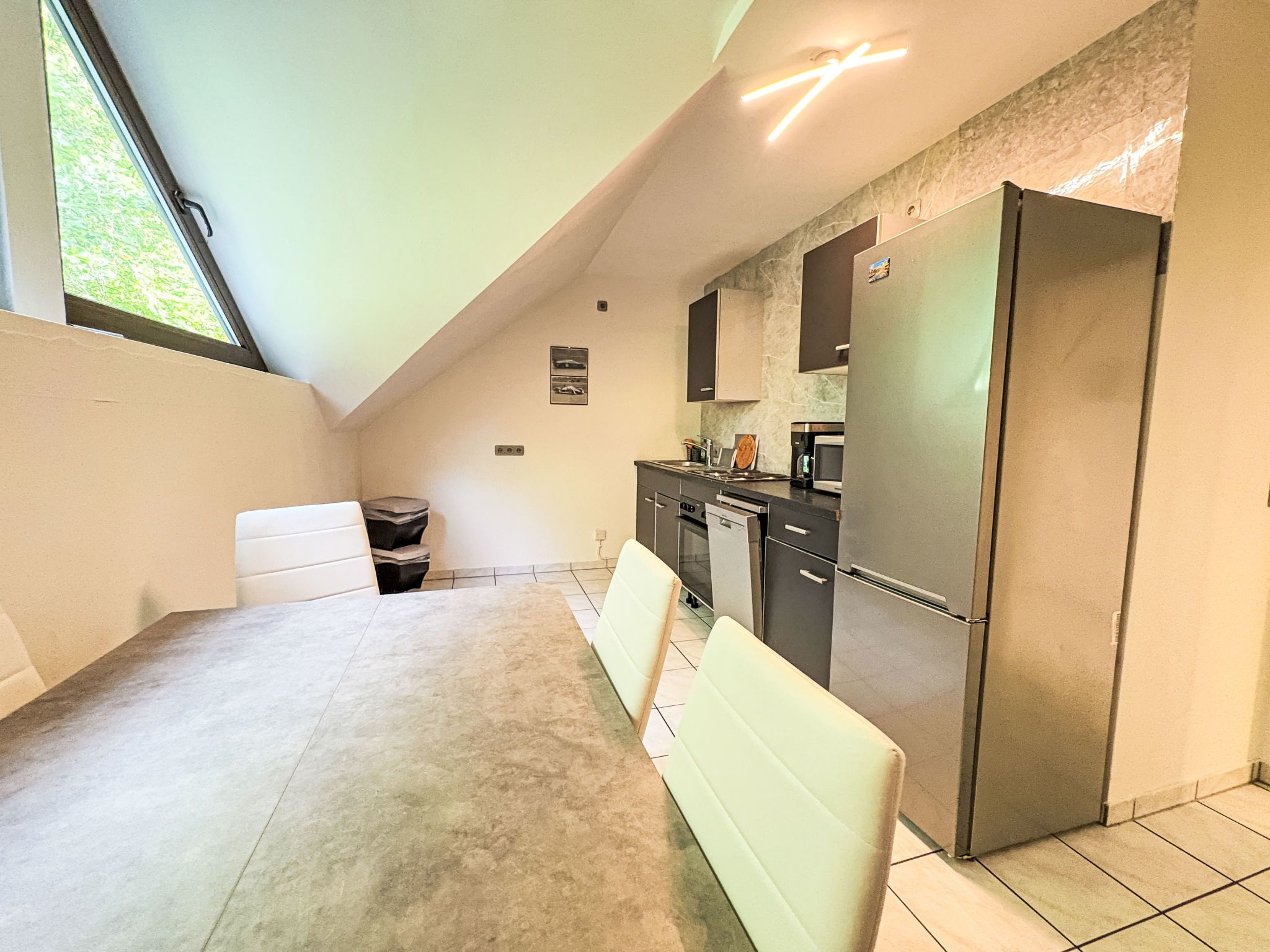 A compact kitchen with a refrigerator, microwave, and stove. There is a dining area with a table and chairs.