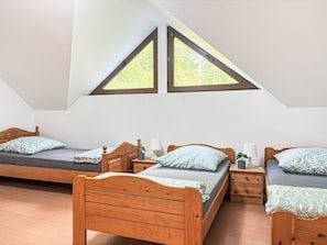 A bedroom with two wooden beds, a skylight, and a small bedside table with a lamp.