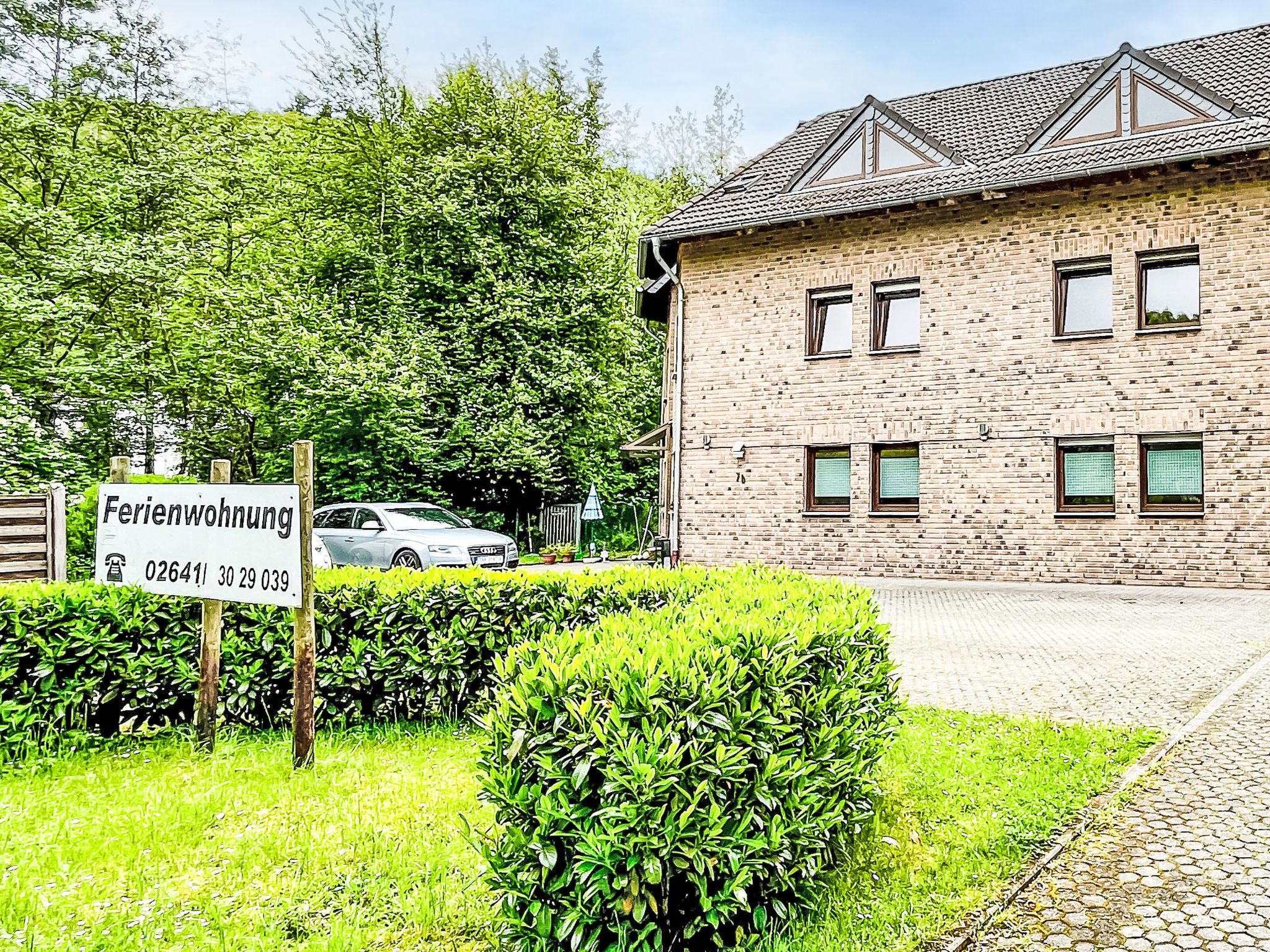 Un bâtiment en briques avec de nombreuses fenêtres, une enseigne et une voiture garée devant.