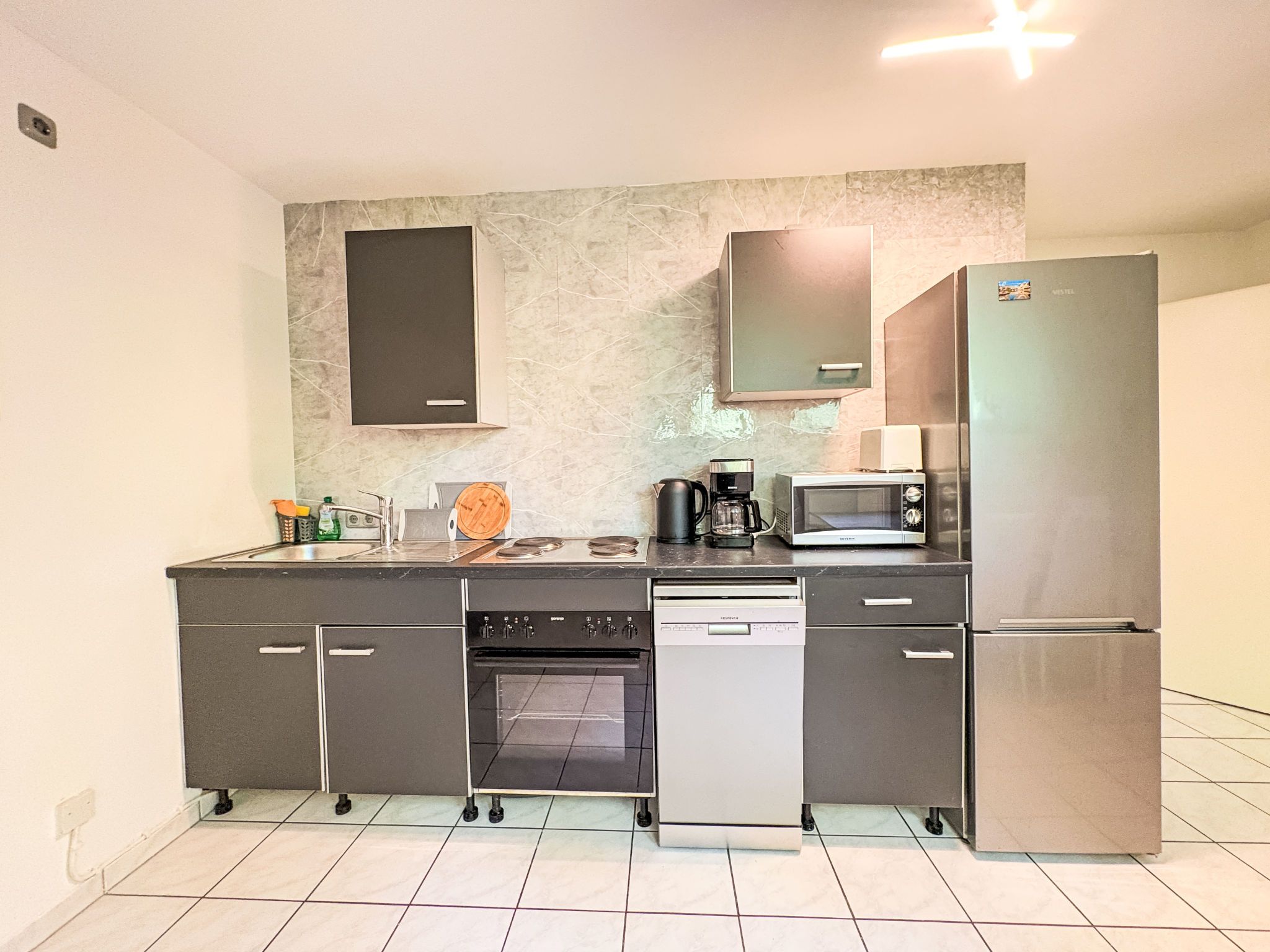 A compact kitchen with a built-in oven, microwave, and refrigerator.