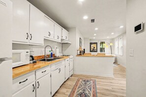 Una cocina moderna con armarios blancos, microondas, lavaplatos y estufa.