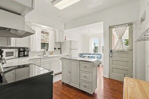 A modern kitchen with white cabinetry, a microwave, a coffee maker, and a refrigerator. - Historic Omaha Gem  4BR  Near UNMC + Midtown (Omaha)