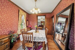 Une salle à manger avec une table dressée pour quatre personnes, un lustre et un grand miroir.