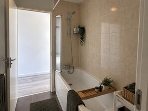 A modern bathroom with a bathtub, shower, and a glass door leading to a balcony. - Dartford House for Large Groups Near Bluewater (Dartford)