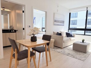 A modern living room with a dining table, chairs, a sofa, and a coffee table. There is a window with a view of buildings. - Downtown Miami Oasis Pool, Gym & City Views (Miami)