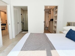 Ein Schlafzimmer mit Bett, begehbarem Kleiderschrank und Badezimmer mit Dusche.