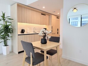 Eine moderne Küche mit Holzschränken, einem Esstisch mit Stühlen und einem Blumentopf.