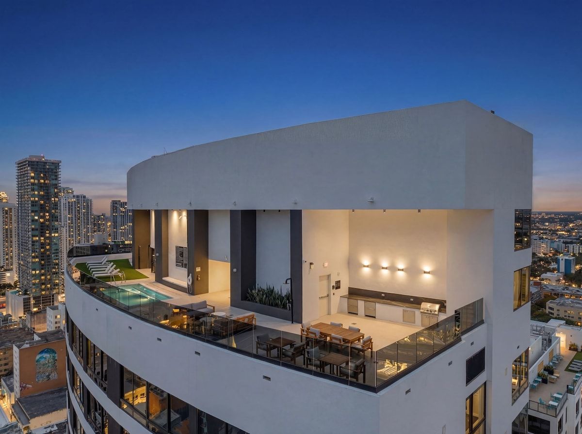 A modern building with a rooftop terrace featuring a pool, dining area, and kitchen.