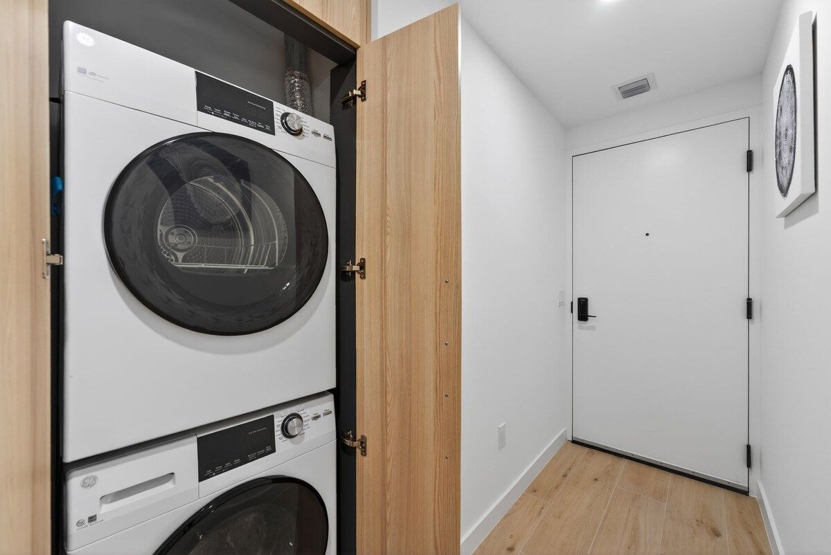 A laundry room with stacked washing machines and a closed door in the background.