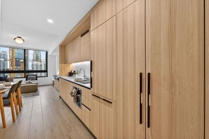 A modern kitchen with wooden cabinets, a built-in oven, and a large window offering a city view. - Downtown Miami Luxe 1BR! (Miami)