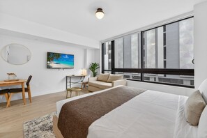 A modern hotel room with a large bed, a desk, a chair, a sofa, and a large window with a view. - Modern Luxe Downtown Stay (Miami)