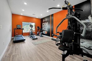 A gym with cardio machines, weightlifting equipment, and a wall-mounted sign. - Magical Family Getaway (Kissimmee)