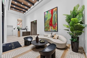 A modern reception area with a sofa, chairs, a coffee table, and a large abstract painting. - Chic Luxury 1BR Oasis (Miami)