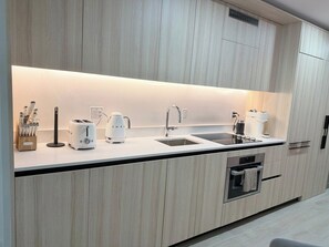 A modern kitchen with a built-in oven, a sink, and a coffee maker. - Chic Luxury 1BR Oasis (Miami)