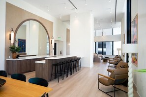 Um saguão de hotel moderno com um bar central, área de estar e um espelho grande.