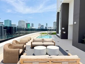 Eine Dachterrasse mit Außenmöbeln, einem Pool und Blick auf die Stadtlandschaft.